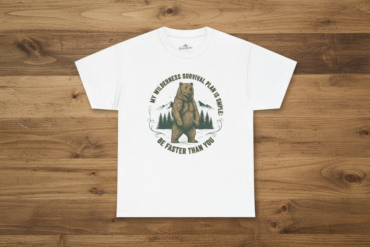 "A man wearing a Camp & Comfort wilderness survival plan tee while standing near a campfire in a pine forest."