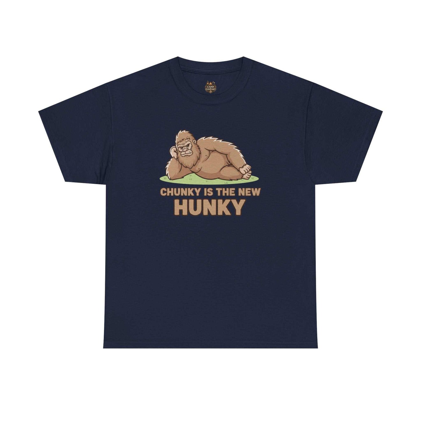 A man wearing the Chunky Is The New Hunky T-Shirt | Funny Bigfoot Sasquatch Tee while leaning against a rustic wooden fence in a mountain setting, showcasing the relaxed fit.
