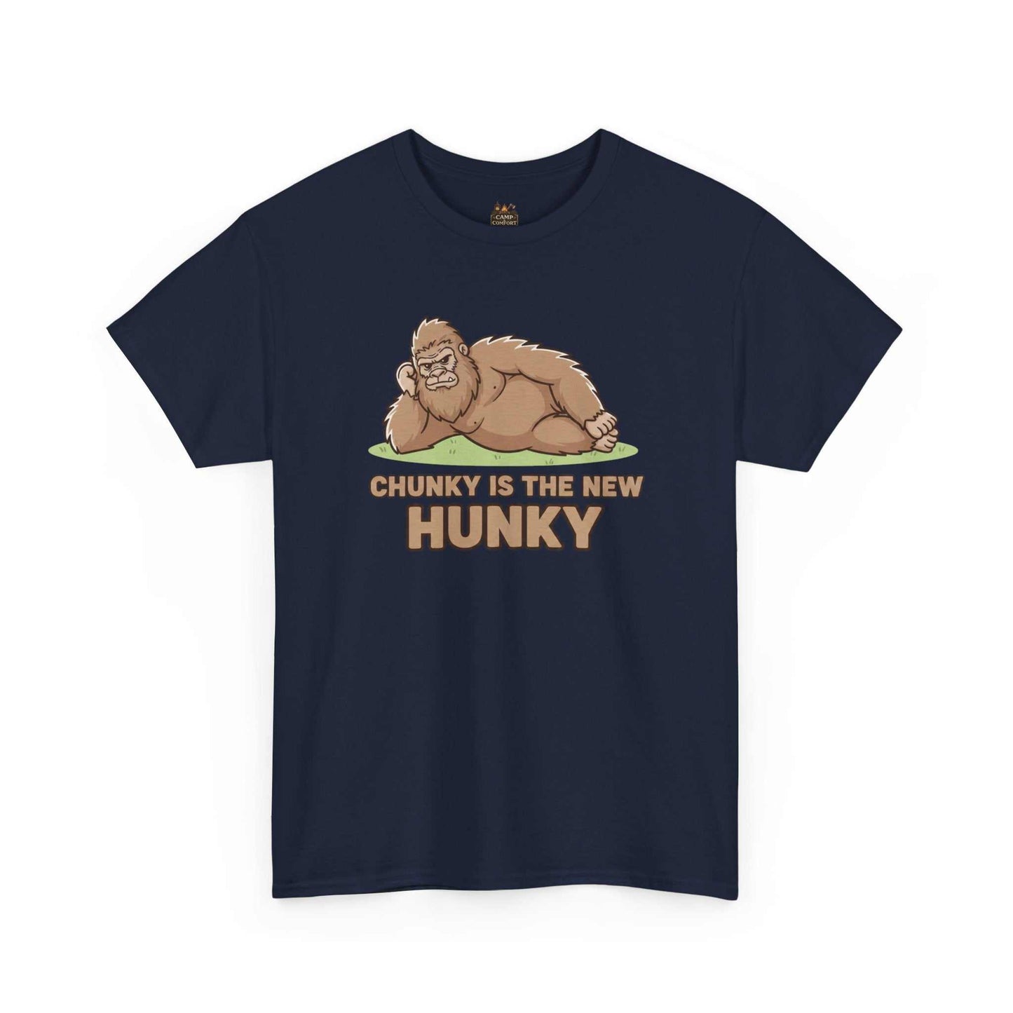 A man wearing the Chunky Is The New Hunky T-Shirt | Funny Bigfoot Sasquatch Tee while leaning against a rustic wooden fence in a mountain setting, showcasing the relaxed fit.