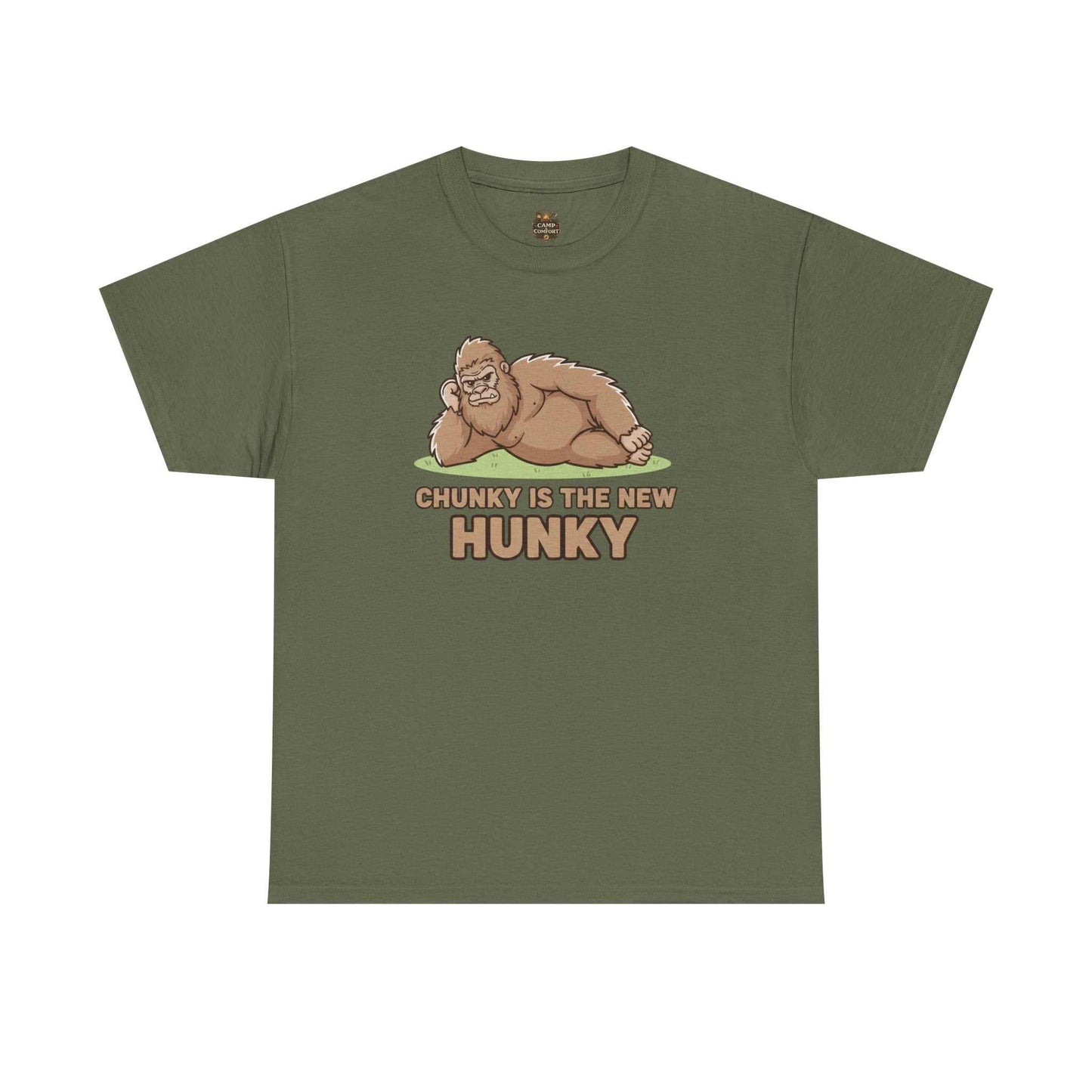 A man wearing the Chunky Is The New Hunky T-Shirt | Funny Bigfoot Sasquatch Tee while leaning against a rustic wooden fence in a mountain setting, showcasing the relaxed fit.