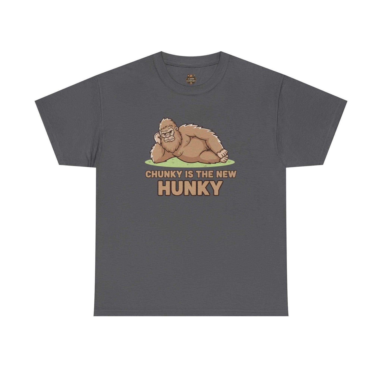 A man wearing the Chunky Is The New Hunky T-Shirt | Funny Bigfoot Sasquatch Tee while leaning against a rustic wooden fence in a mountain setting, showcasing the relaxed fit.